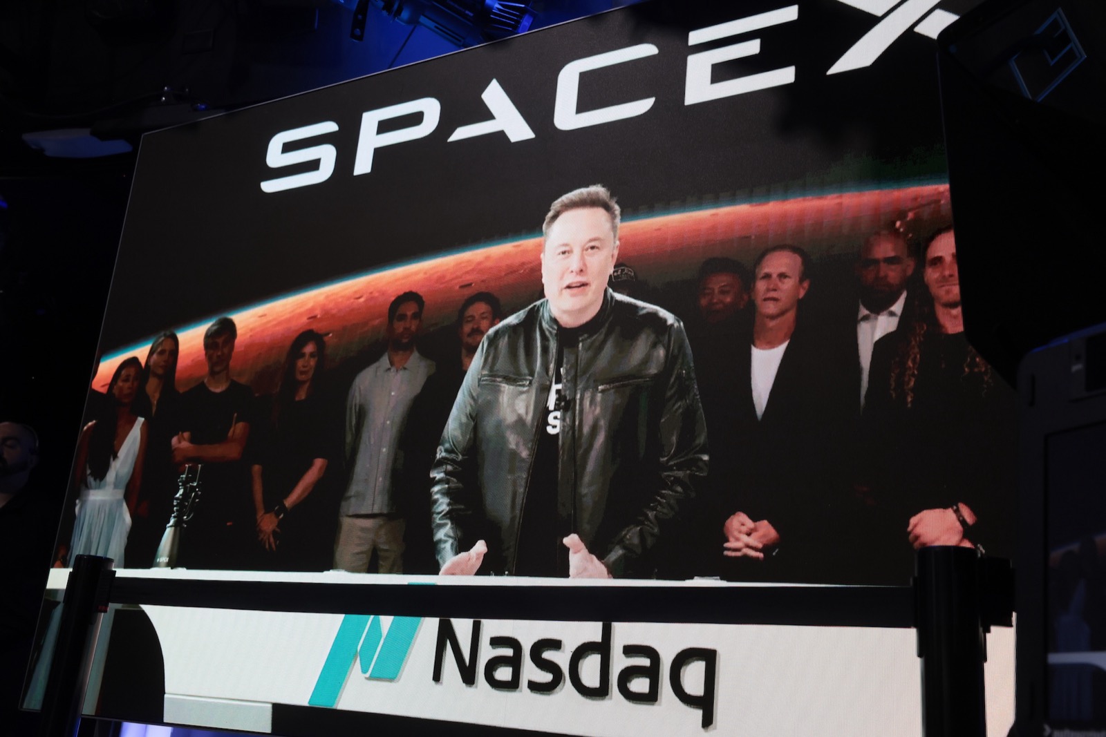 Илон Маск на экране Nasdaq во время IPO SpaceX — за ним совет директоров и логотип компании